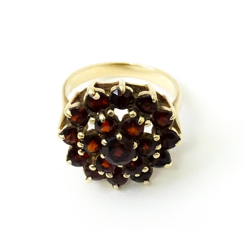 740 - A 9ct gold cocktail ring set with 19 garnets in a cluster setting. Ring size approx. O