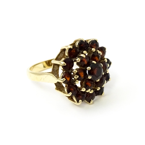 740 - A 9ct gold cocktail ring set with 19 garnets in a cluster setting. Ring size approx. O