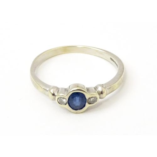 747 - A 9ct white gold ring set with central sapphire flanked by diamonds. Maker Alfred Terry Ltd  Ring si... 