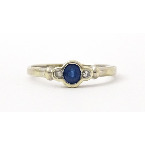 747 - A 9ct white gold ring set with central sapphire flanked by diamonds. Maker Alfred Terry Ltd  Ring si... 