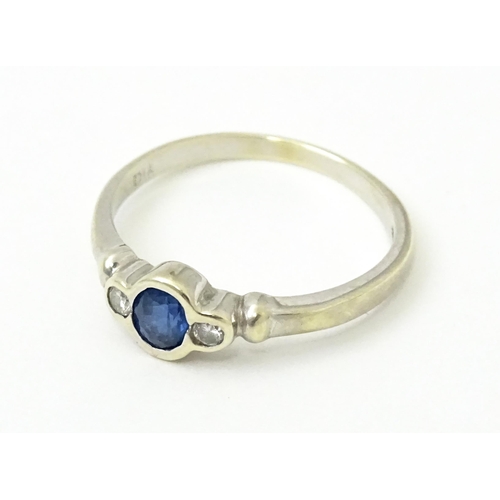 747 - A 9ct white gold ring set with central sapphire flanked by diamonds. Maker Alfred Terry Ltd  Ring si... 