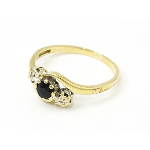 749 - A 9ct gold ring set with central sapphire flanked by diamonds. Ring size approx. Q 1/2