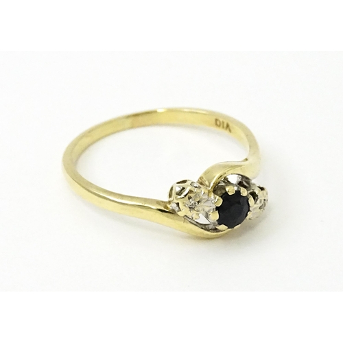 749 - A 9ct gold ring set with central sapphire flanked by diamonds. Ring size approx. Q 1/2