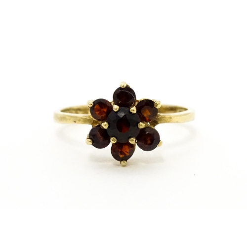 753 - A 9ct gold ring set with garnets in a floral setting. Ring size approx. O