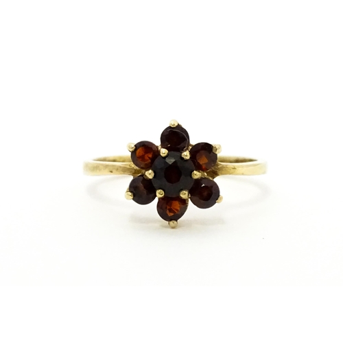 753 - A 9ct gold ring set with garnets in a floral setting. Ring size approx. O