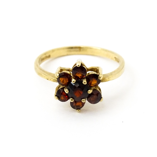 753 - A 9ct gold ring set with garnets in a floral setting. Ring size approx. O