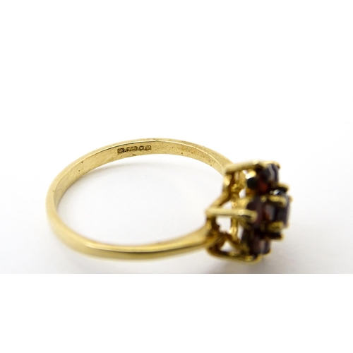 753 - A 9ct gold ring set with garnets in a floral setting. Ring size approx. O