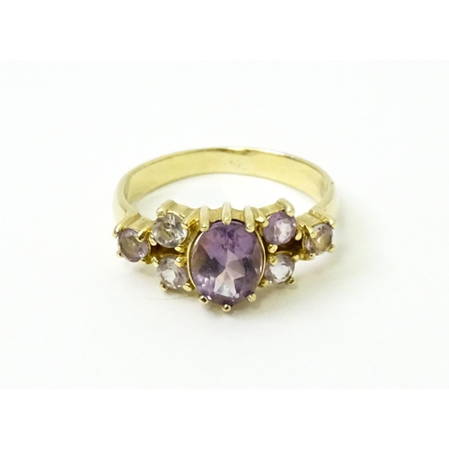 757 - A 14ct gold ring set with central amethyst flanked by further amethysts. Ring size approx. N