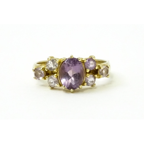 757 - A 14ct gold ring set with central amethyst flanked by further amethysts. Ring size approx. N