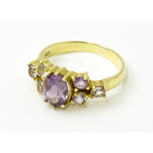 757 - A 14ct gold ring set with central amethyst flanked by further amethysts. Ring size approx. N