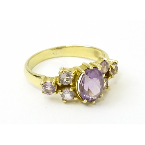 757 - A 14ct gold ring set with central amethyst flanked by further amethysts. Ring size approx. N