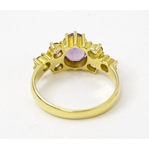 757 - A 14ct gold ring set with central amethyst flanked by further amethysts. Ring size approx. N