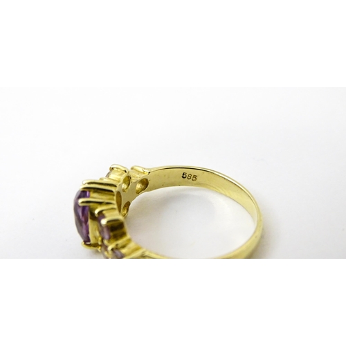 757 - A 14ct gold ring set with central amethyst flanked by further amethysts. Ring size approx. N