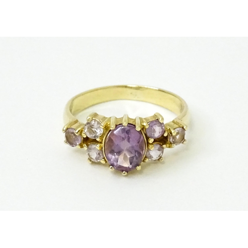 757 - A 14ct gold ring set with central amethyst flanked by further amethysts. Ring size approx. N