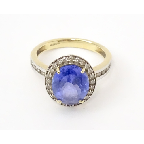 765 - A 9ct gold ring set with central tanzanite bordered by diamonds. Ring size approx. N 1/2