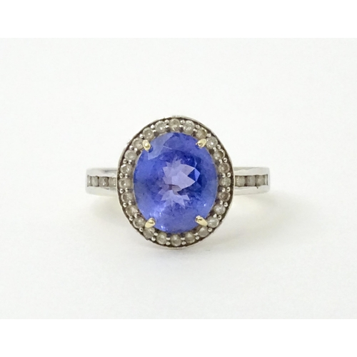 765 - A 9ct gold ring set with central tanzanite bordered by diamonds. Ring size approx. N 1/2