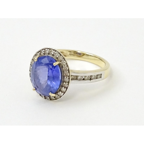 765 - A 9ct gold ring set with central tanzanite bordered by diamonds. Ring size approx. N 1/2