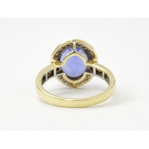 765 - A 9ct gold ring set with central tanzanite bordered by diamonds. Ring size approx. N 1/2