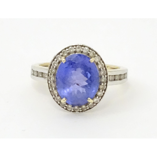 765 - A 9ct gold ring set with central tanzanite bordered by diamonds. Ring size approx. N 1/2