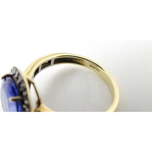 765 - A 9ct gold ring set with central tanzanite bordered by diamonds. Ring size approx. N 1/2