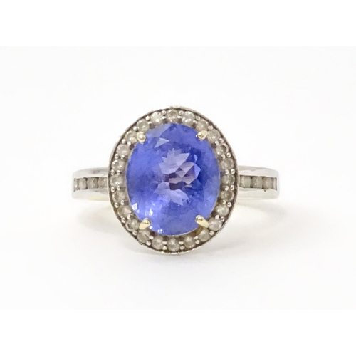 765 - A 9ct gold ring set with central tanzanite bordered by diamonds. Ring size approx. N 1/2