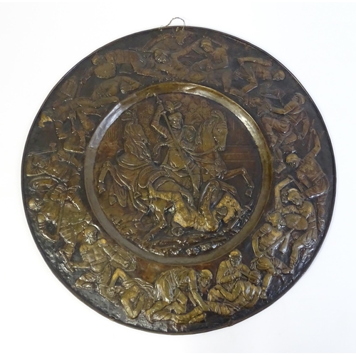 1507 - A large 20thC brass charger with relief decoration depicting Roman soldiers in battle, possibly depi... 