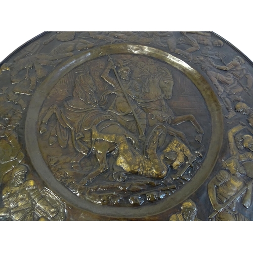 1507 - A large 20thC brass charger with relief decoration depicting Roman soldiers in battle, possibly depi... 