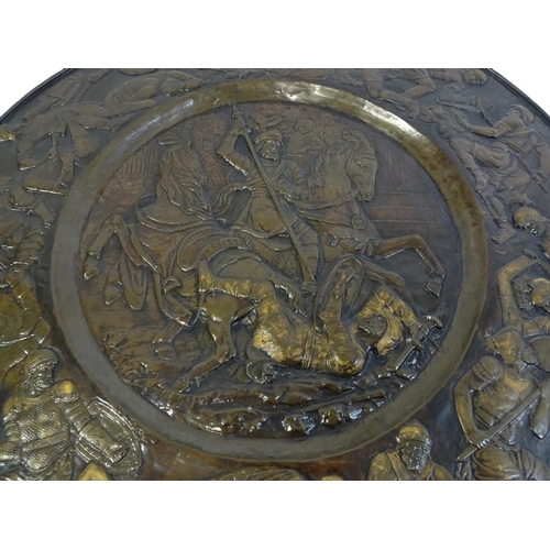 1507 - A large 20thC brass charger with relief decoration depicting Roman soldiers in battle, possibly depi... 