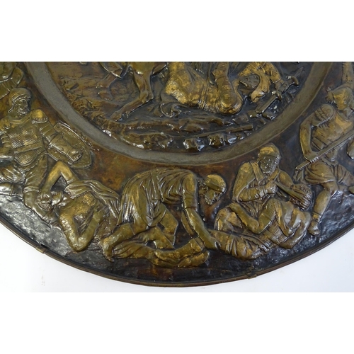 1507 - A large 20thC brass charger with relief decoration depicting Roman soldiers in battle, possibly depi... 