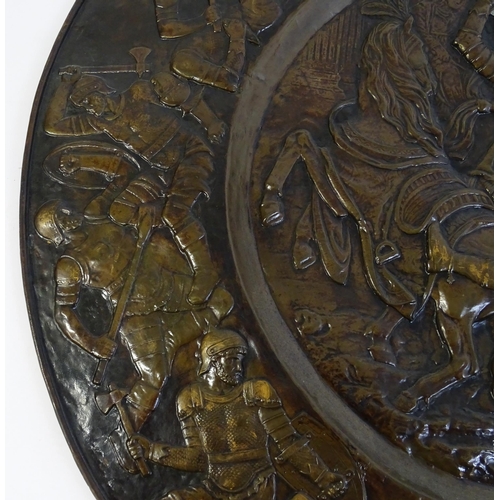 1507 - A large 20thC brass charger with relief decoration depicting Roman soldiers in battle, possibly depi... 