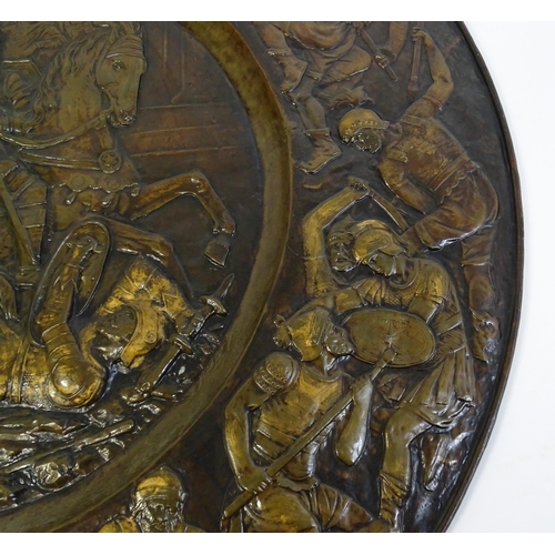 1507 - A large 20thC brass charger with relief decoration depicting Roman soldiers in battle, possibly depi... 