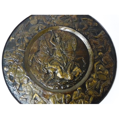 1507 - A large 20thC brass charger with relief decoration depicting Roman soldiers in battle, possibly depi... 