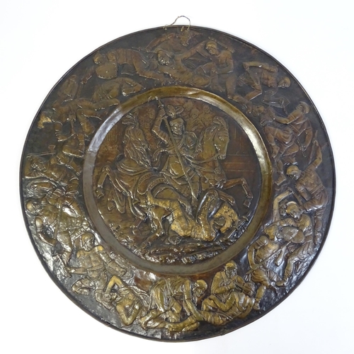 1507 - A large 20thC brass charger with relief decoration depicting Roman soldiers in battle, possibly depi... 