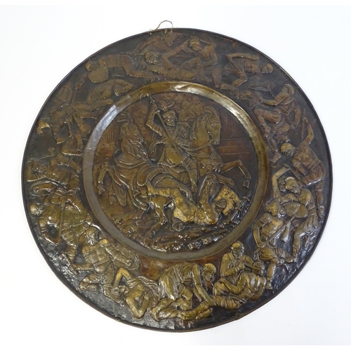 1507 - A large 20thC brass charger with relief decoration depicting Roman soldiers in battle, possibly depi... 