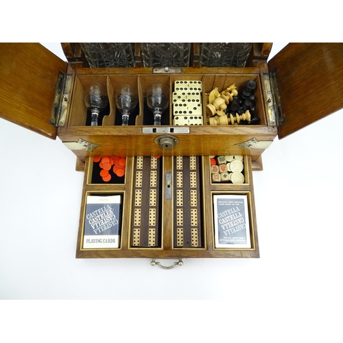 1532 - A Victorian oak tantalus / games compendium with silver plate mounts. With three glass decanters and... 