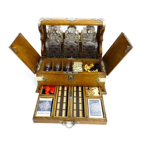 1532 - A Victorian oak tantalus / games compendium with silver plate mounts. With three glass decanters and... 