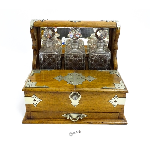 1532 - A Victorian oak tantalus / games compendium with silver plate mounts. With three glass decanters and... 