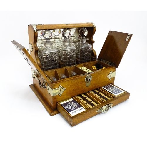 1532 - A Victorian oak tantalus / games compendium with silver plate mounts. With three glass decanters and... 