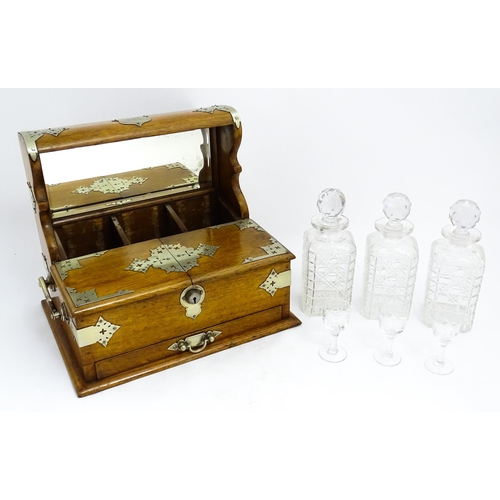 1532 - A Victorian oak tantalus / games compendium with silver plate mounts. With three glass decanters and... 