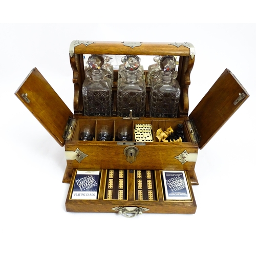 1532 - A Victorian oak tantalus / games compendium with silver plate mounts. With three glass decanters and... 