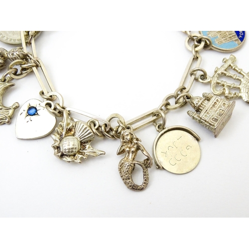 962 - A silver and white metal charm bracelet set with various silver and white metal charms to include a ... 