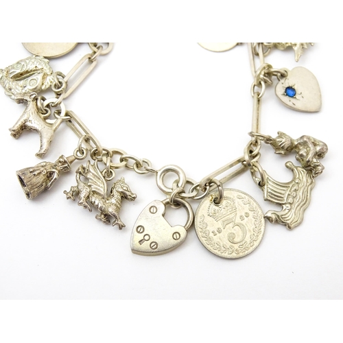 962 - A silver and white metal charm bracelet set with various silver and white metal charms to include a ... 