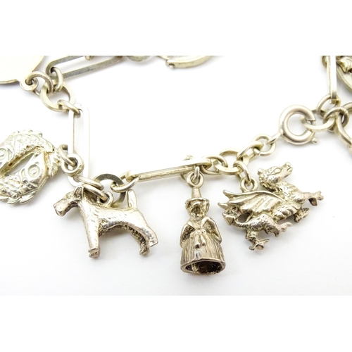 962 - A silver and white metal charm bracelet set with various silver and white metal charms to include a ... 