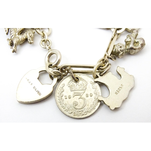 962 - A silver and white metal charm bracelet set with various silver and white metal charms to include a ... 