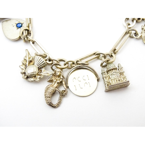 962 - A silver and white metal charm bracelet set with various silver and white metal charms to include a ... 