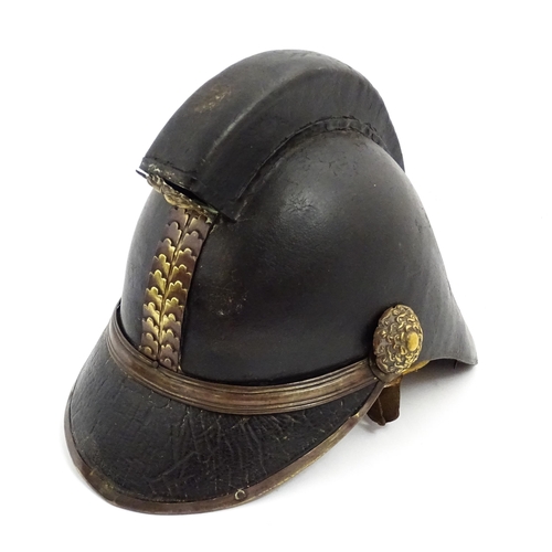 1469 - A 19thC fireman's helmet, the black leather shell with visor and rear brim, decorated with cockades,... 