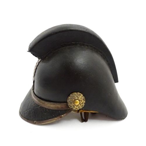 1469 - A 19thC fireman's helmet, the black leather shell with visor and rear brim, decorated with cockades,... 