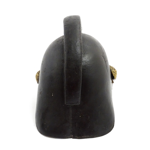 1469 - A 19thC fireman's helmet, the black leather shell with visor and rear brim, decorated with cockades,... 