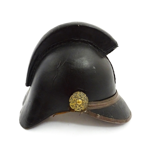 1469 - A 19thC fireman's helmet, the black leather shell with visor and rear brim, decorated with cockades,... 