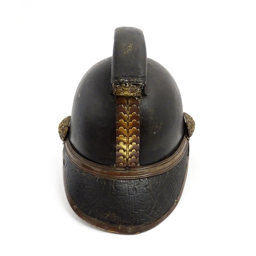 1469 - A 19thC fireman's helmet, the black leather shell with visor and rear brim, decorated with cockades,... 